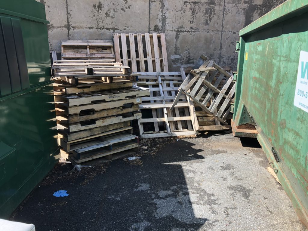 Stack of wooden pallets behind a dumpster